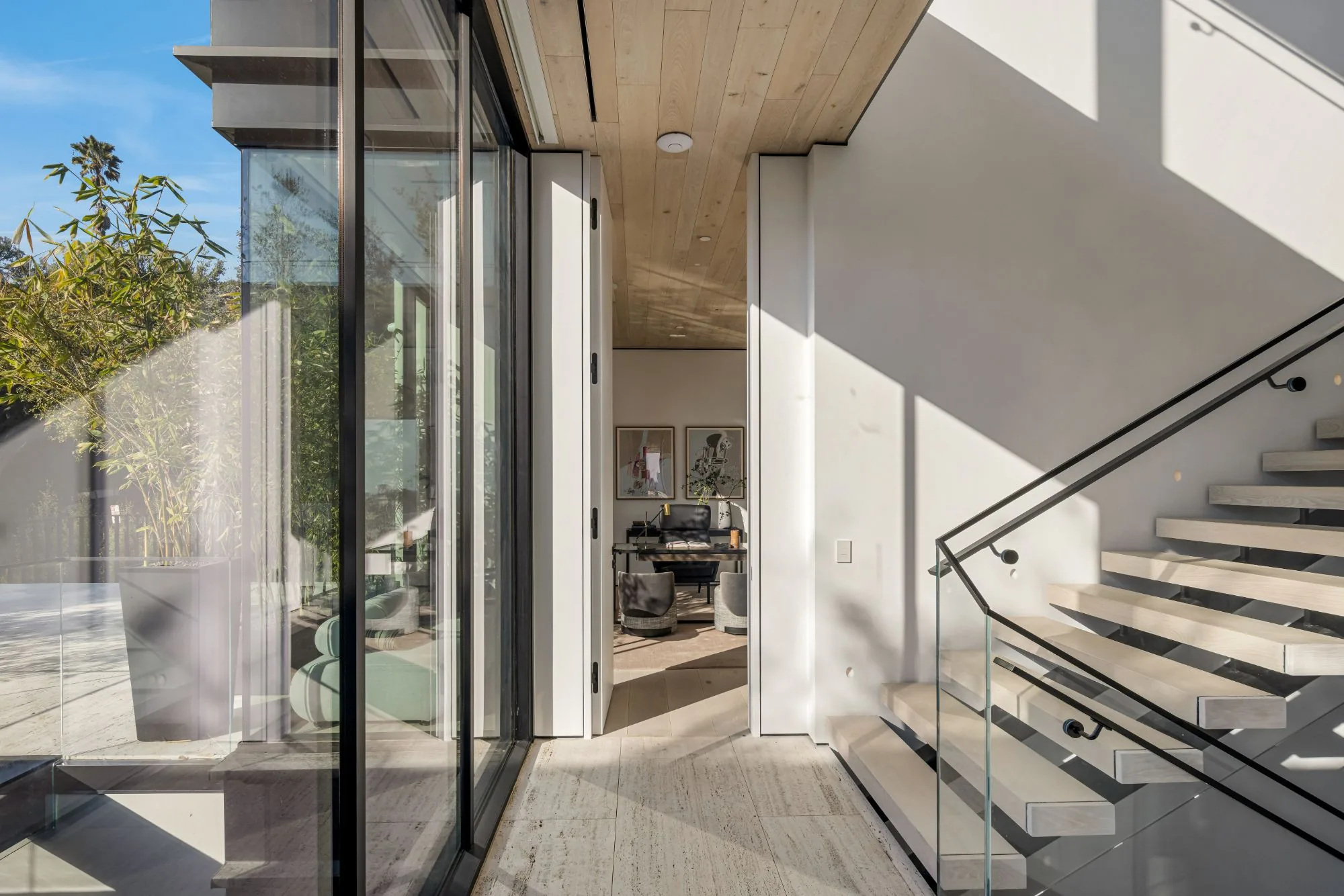 Floating stair, full-height doors and wood-plank ceiling beside a glass wall at the Laurel Way custom home in Beverly Hills