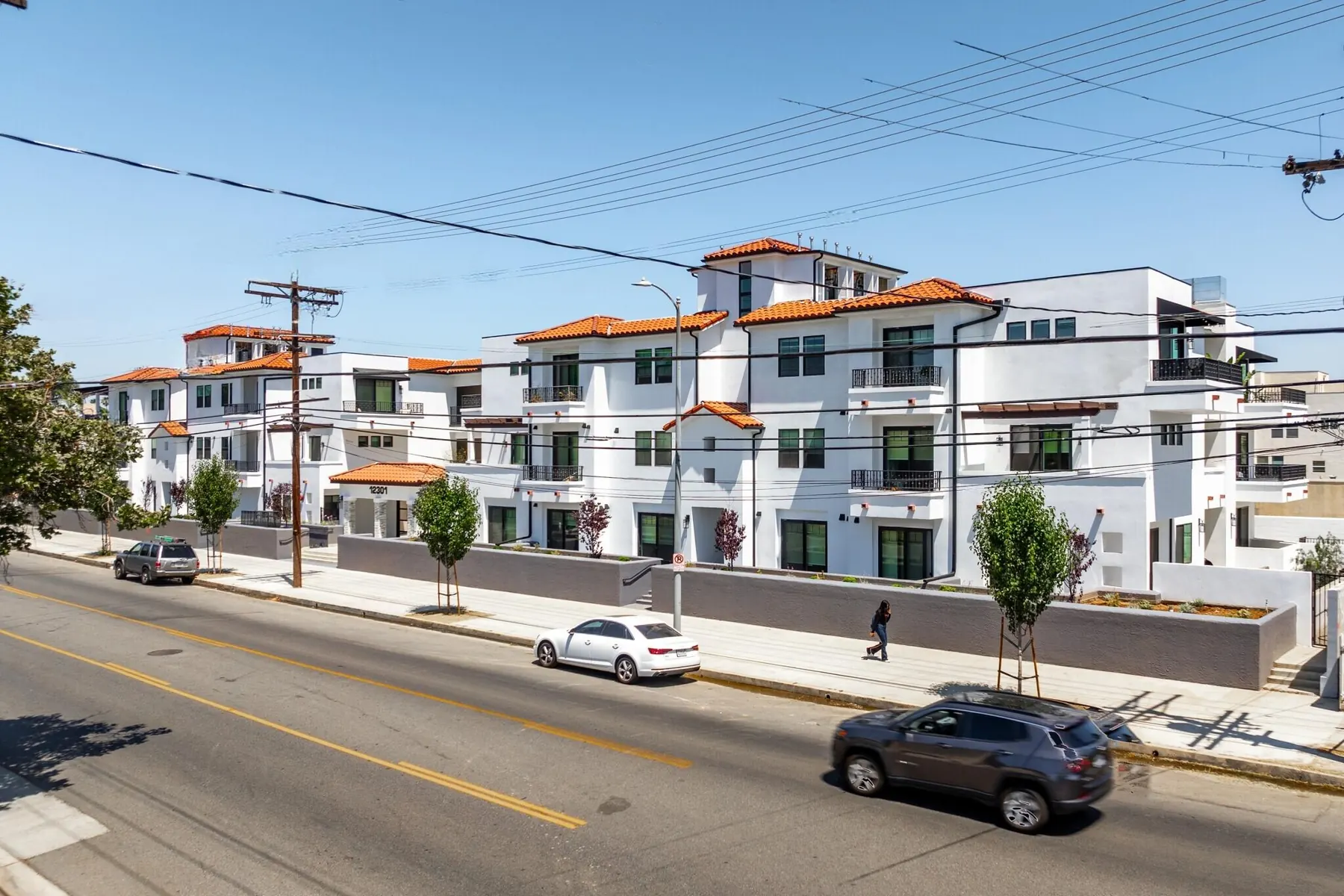 Street view of the white stucco walls, balconies and tile roofs of M Street Residences, a multi-unit building Valley Vista Builders built in Valley Village
