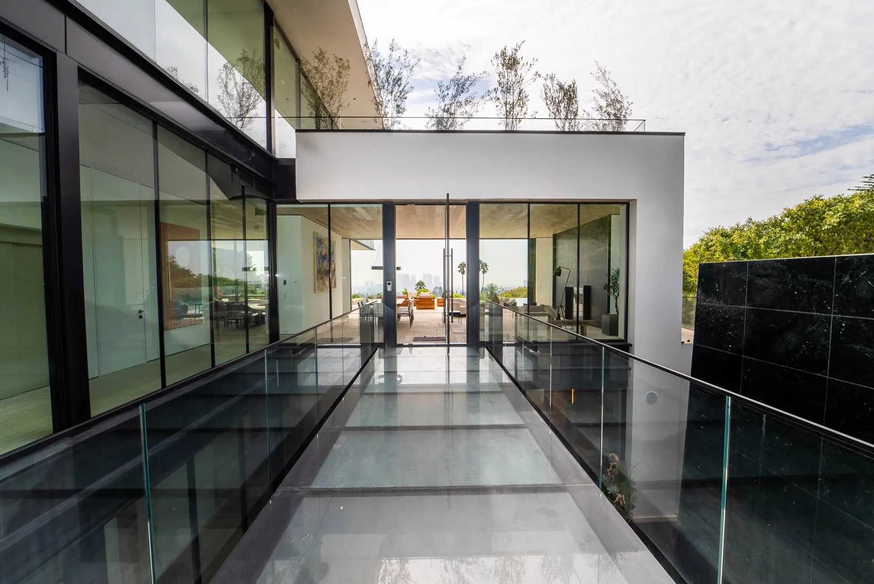 Glass skybridge between the two wings of the Laurel Way custom home in Beverly Hills, built by Valley Vista Builders, under a cloudy sky