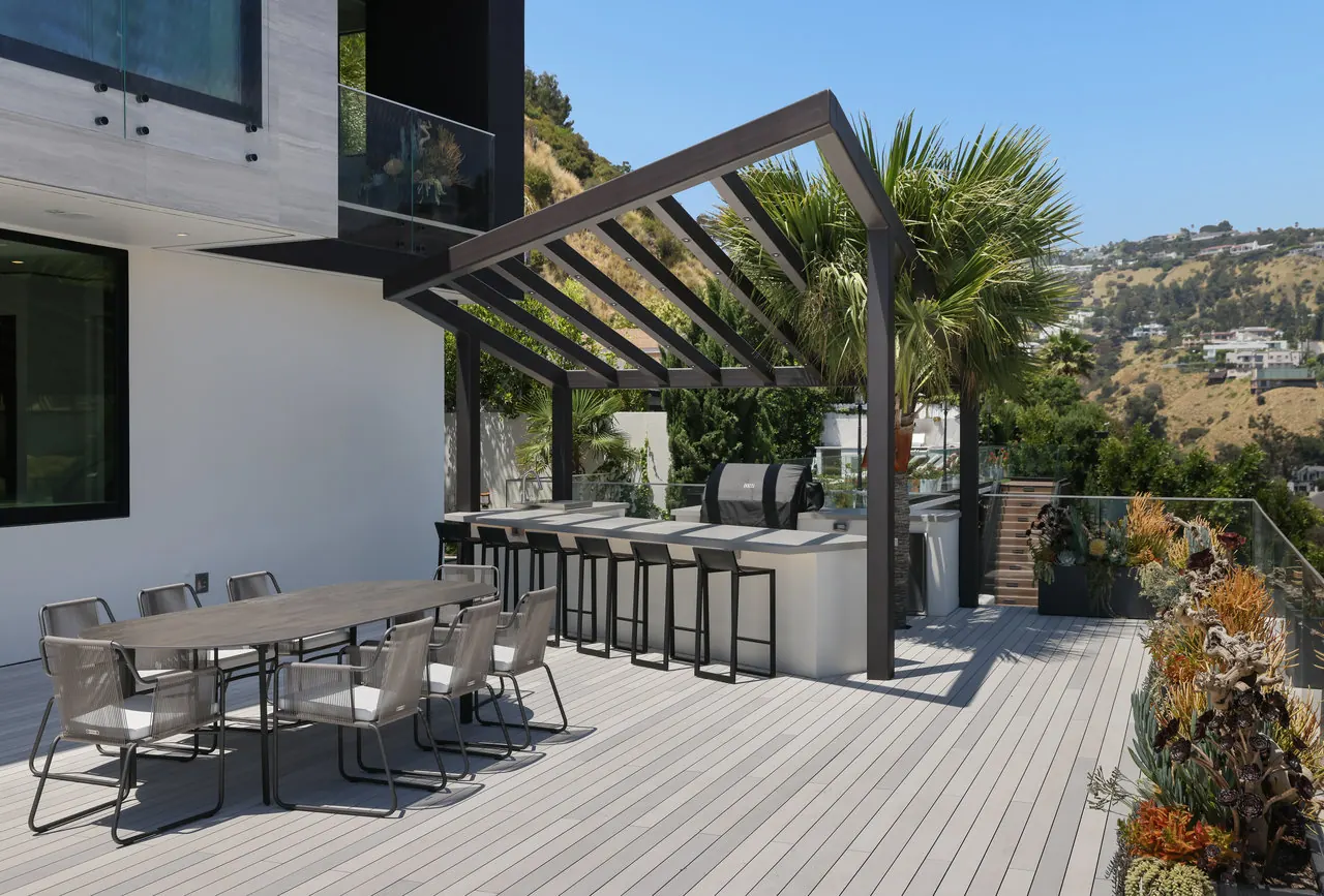 Terrace kitchen and outdoor dining deck at the Laurel View Residence, a Hollywood Hills home built by Valley Vista Builders, looking out over the hillside