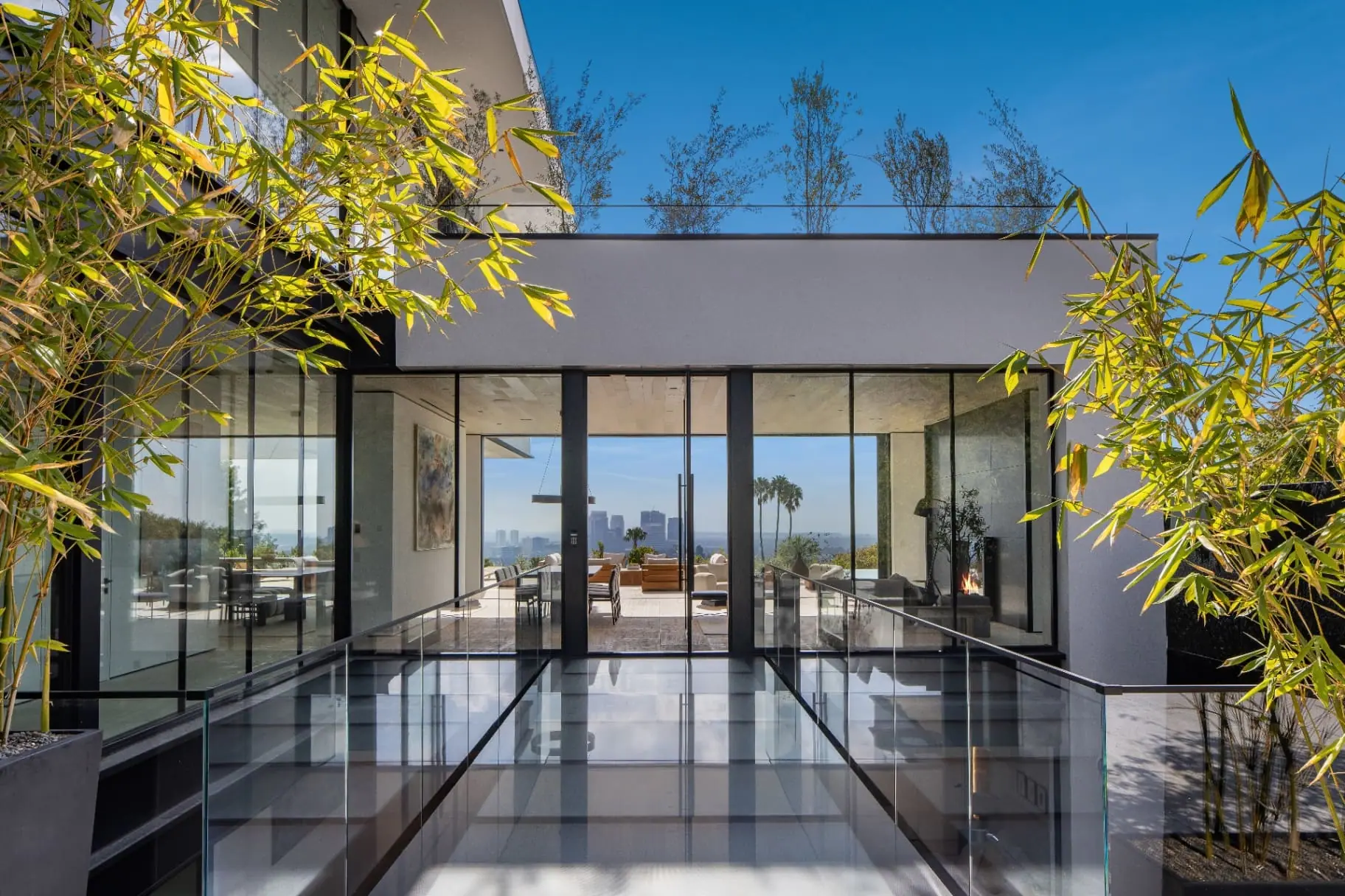 Glass-floored skybridge in daylight leading to the glass-walled living room of the Laurel Way custom home in Beverly Hills, built by Valley Vista Builders