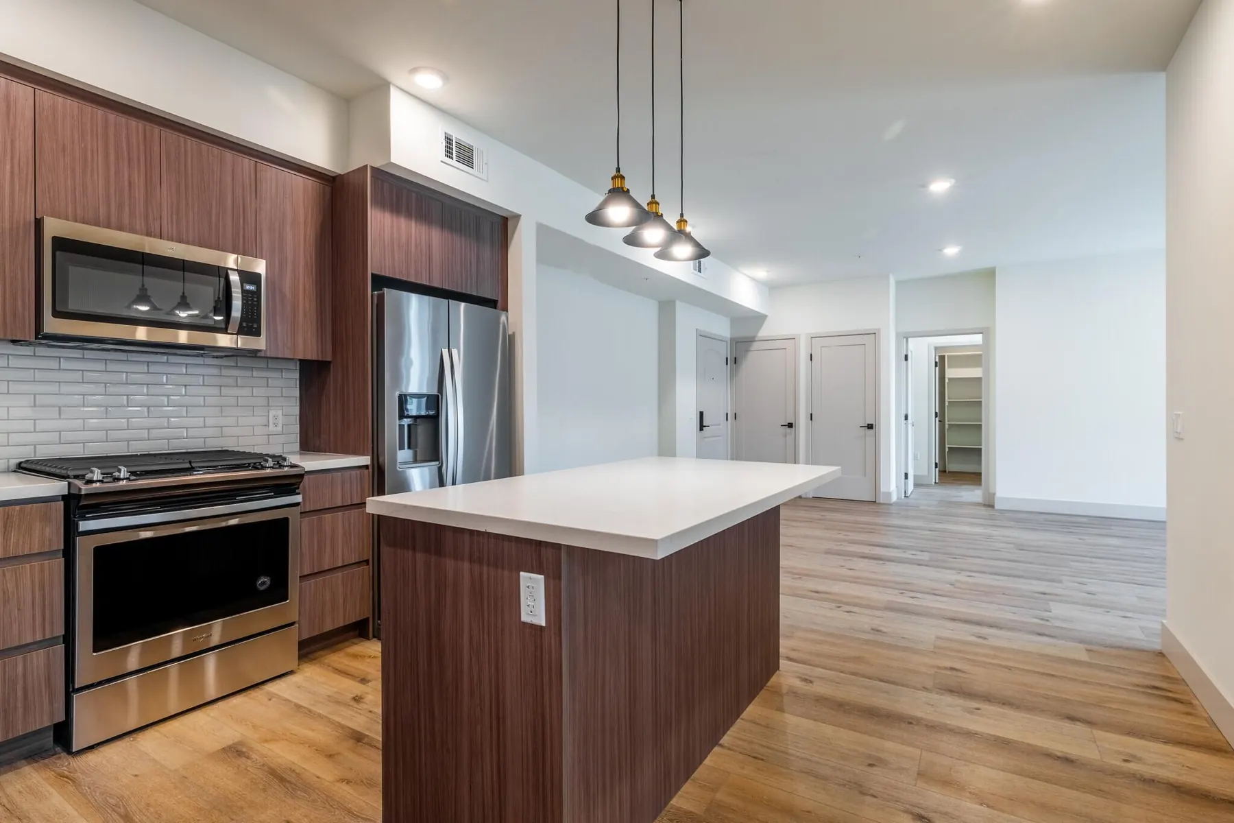 Kitchen with wood-grain cabinets, a white-topped island and stainless appliances in a unit at M Street Residences, a multi-unit building Valley Vista Builders built in Valley Village