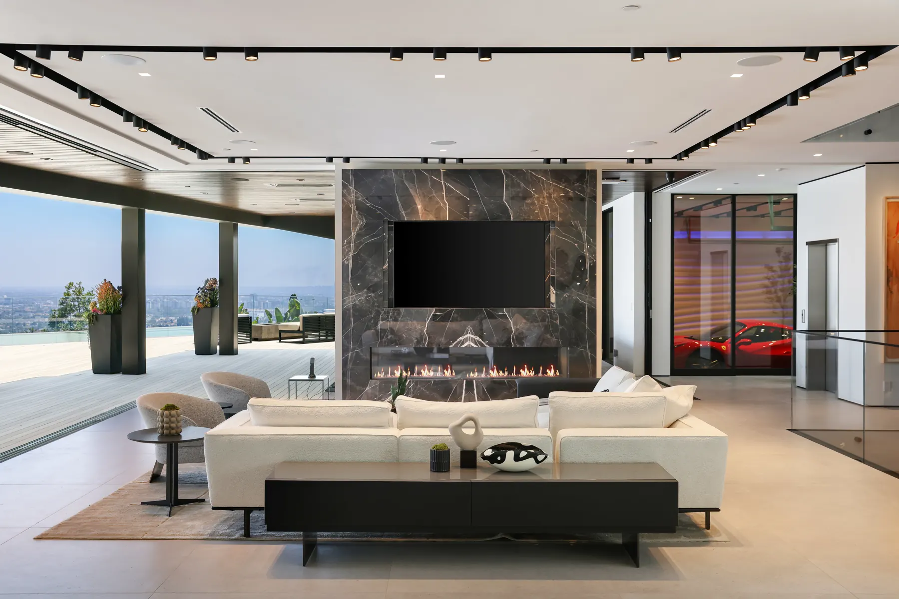 Living room with a marble fireplace wall, open to a terrace above the city, at the Laurel View Residence, a Hollywood Hills home built by Valley Vista Builders