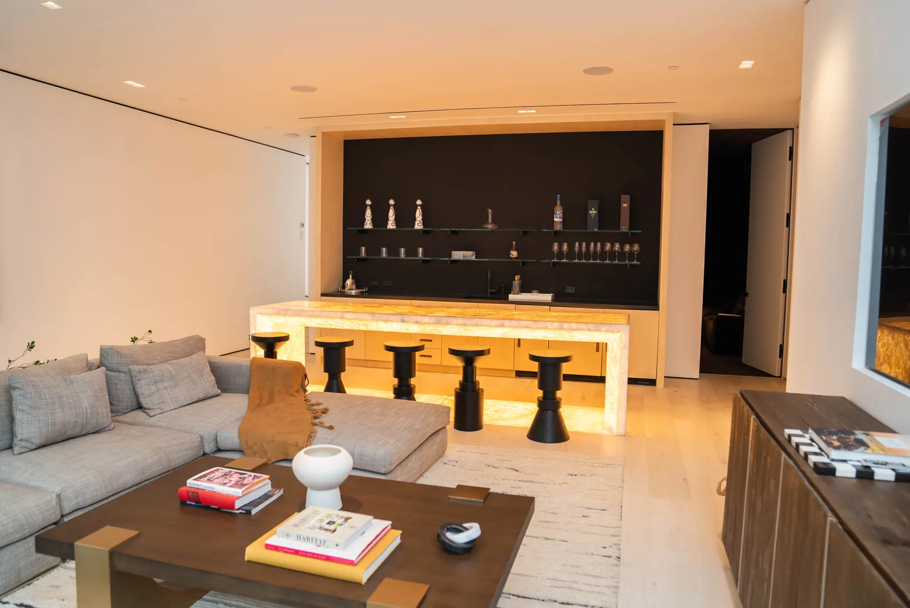 Living room with a sectional sofa facing a backlit onyx bar at the Laurel Way custom home in Beverly Hills, built by Valley Vista Builders